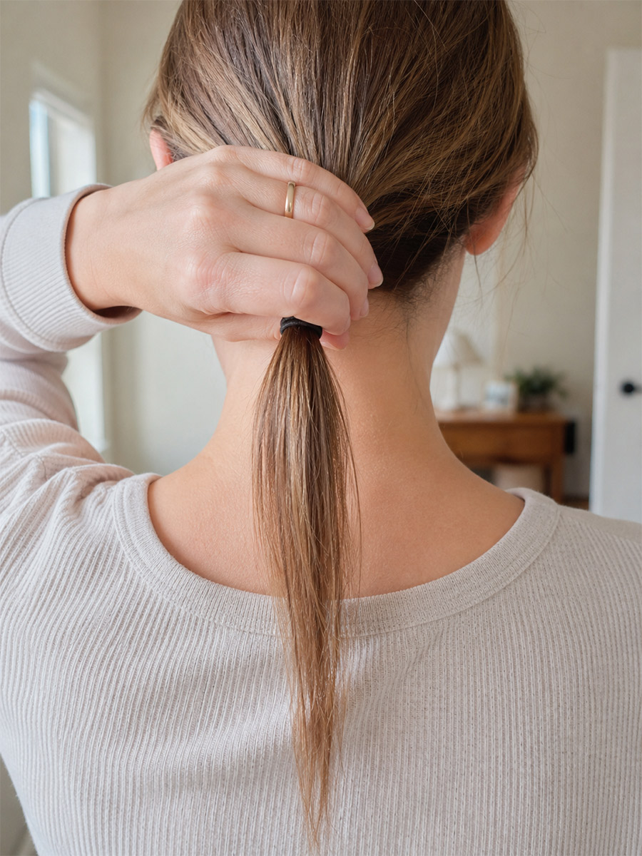 A slender ponytail gathered in one hand, tapering noticeably toward the ends